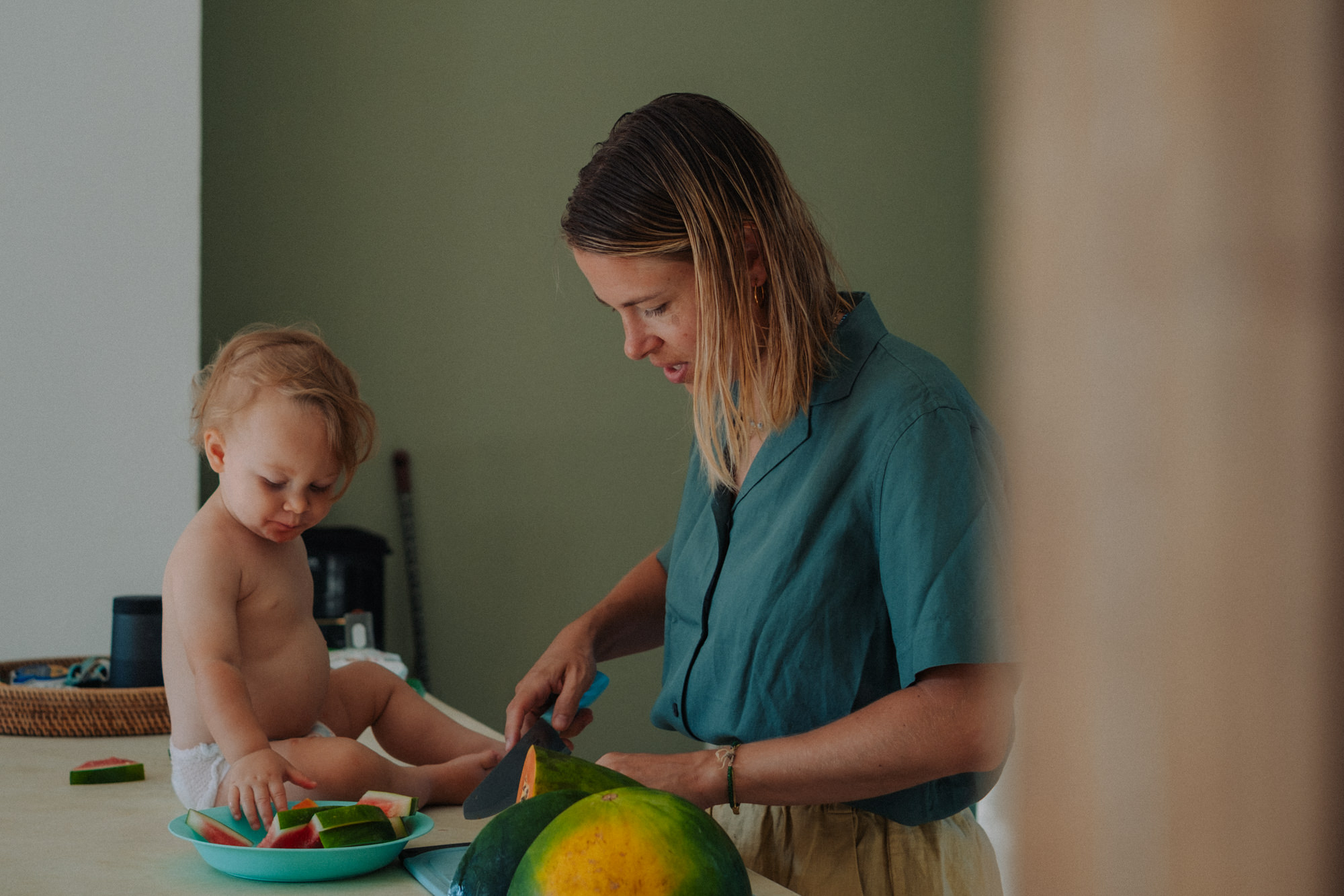 Mutter und Kleinkind schneiden Wassermelone – Familienküche Alltagsmomente
