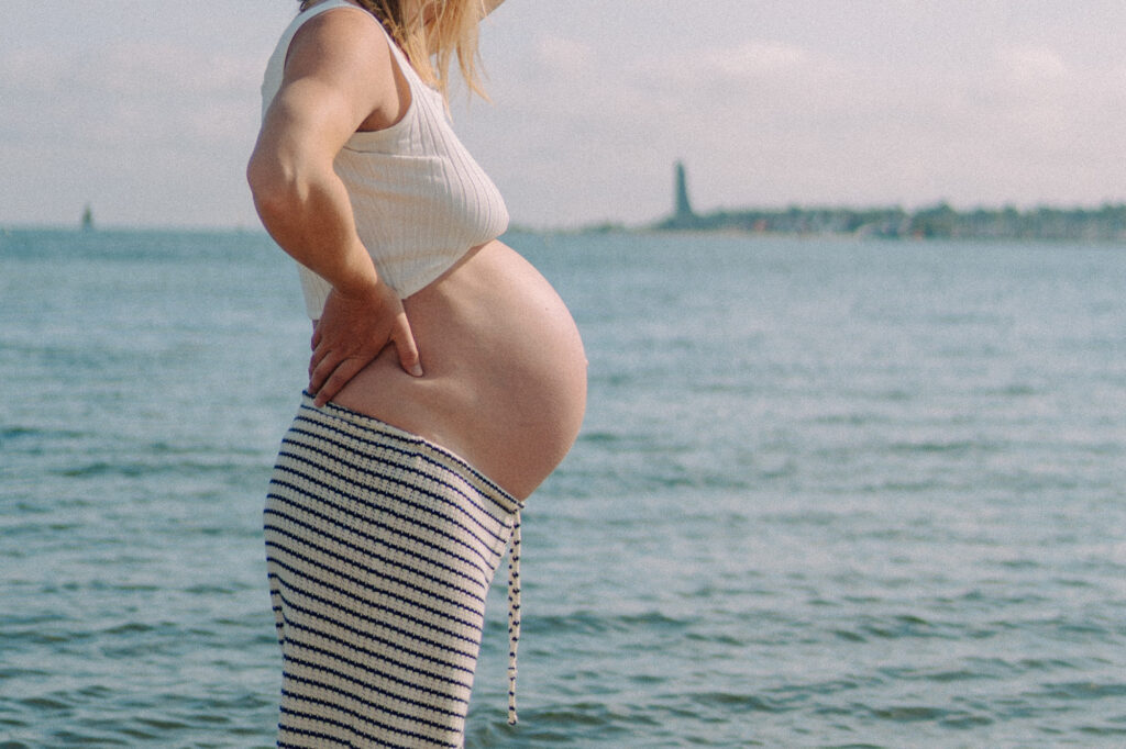Schwangere Frau in entspannter Pose am Strand – Babybauchshooting Kiel