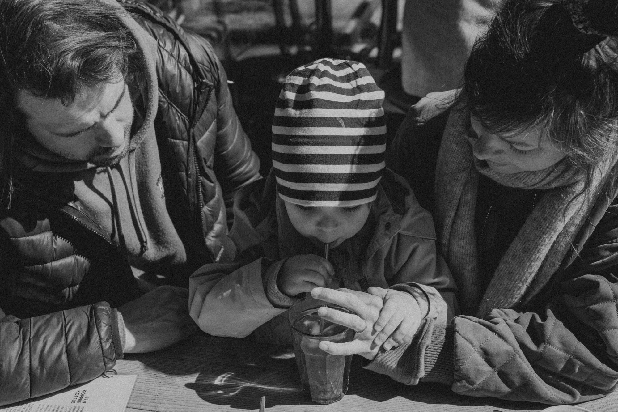 Kind mit Mütze trinkt aus Glas – dokumentarische Kinderfotografie draußen