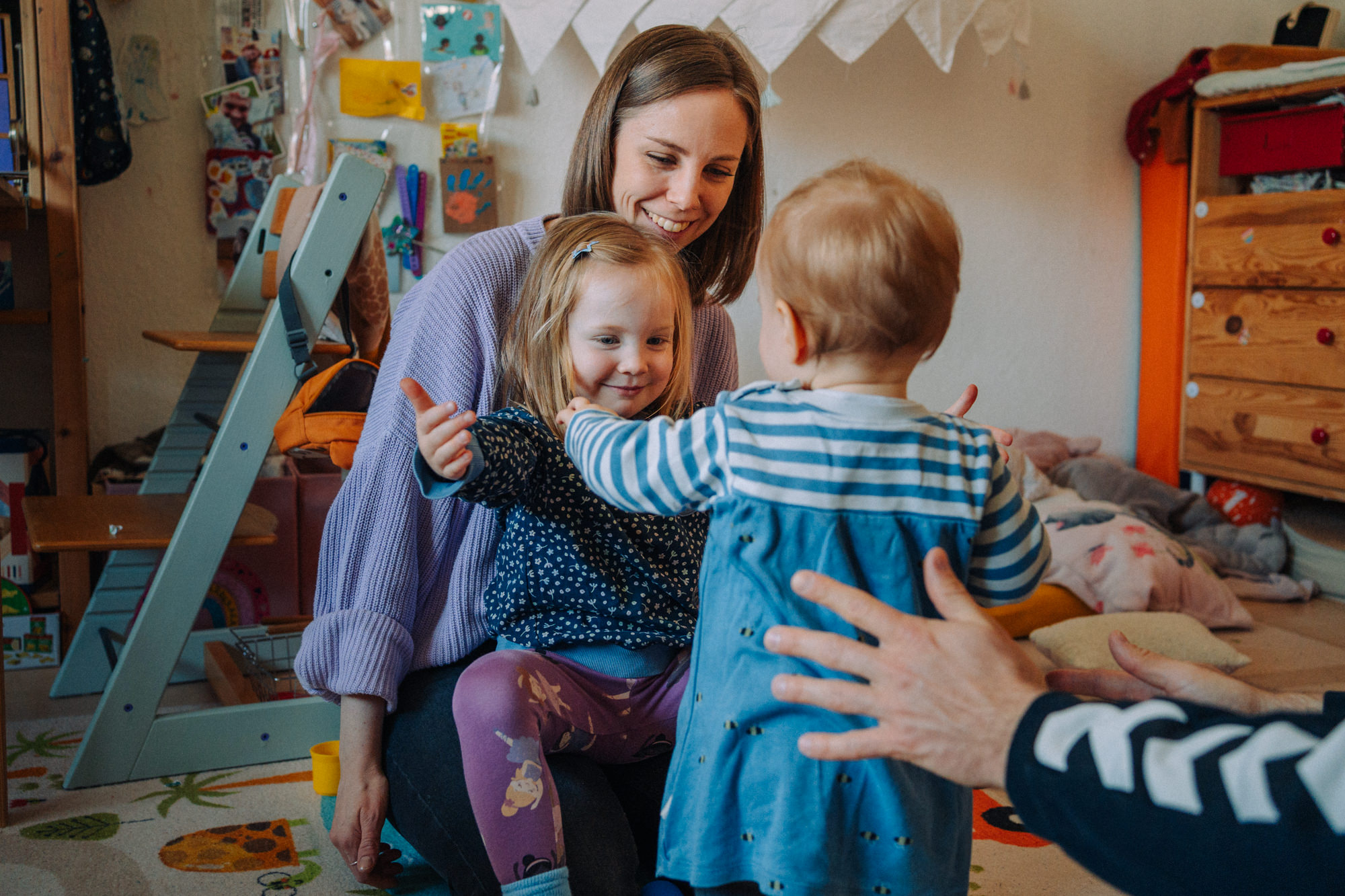 Mutter spielt mit zwei Kleinkindern im Kinderzimmer – lebendige Familienreportage